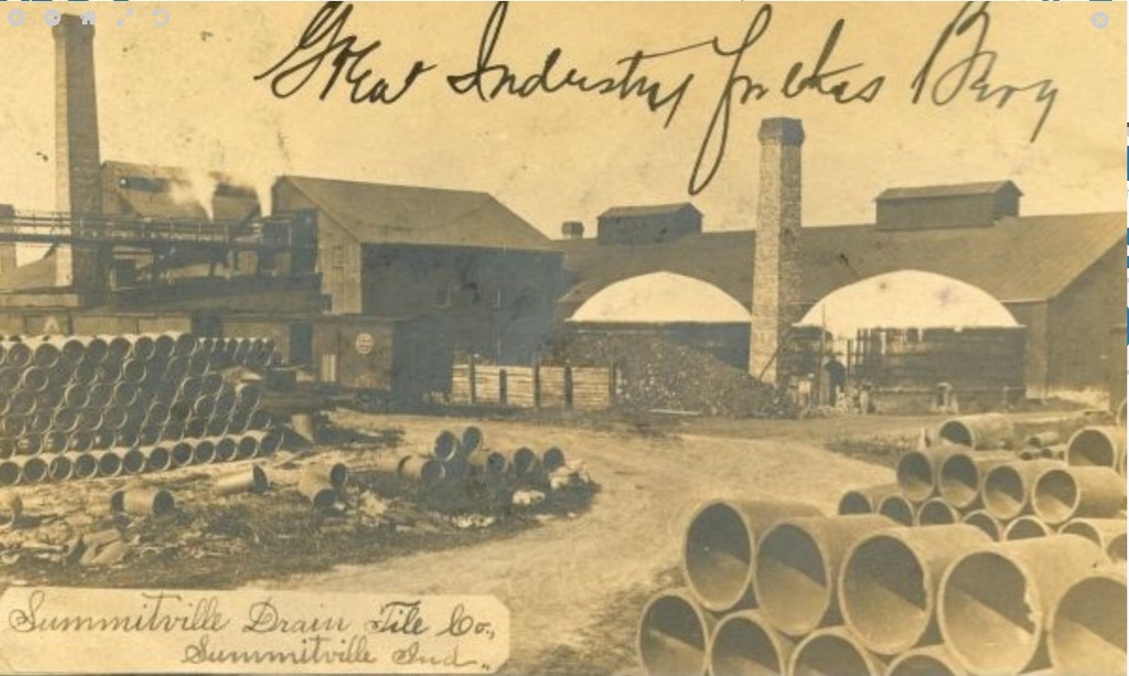 Factory building for Summitville Drain Tile Company, with large drain pipes in the foreground